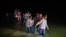 FILE - Migrant families, mostly from Central American countries, wade through shallow waters after being delivered by smugglers on small inflatable rafts on U.S. soil in Roma, Texas, March 24, 2021.