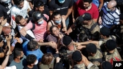 A woman yells at Lebanese soldiers during scuffles with the soldiers who are blocking a road as French President Emmanuel Macron visits the Gemmayzeh neighborhood, which suffered extensive damage from the Tuesday explosion at the seaport, in Beirut.