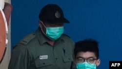 FILE - Pro-democracy activist Joshua Wong, right, leaves Lai Chi Kok Reception center in Hong Kong, on his way to court, Dec. 18, 2020.