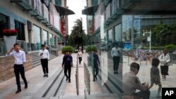 File - People walk by a shopping mall in Shenzhen, China's Guangdong province, Oct. 31, 2019. Shenzhen remains China's biggest goods exporter, but its overseas shipments fell nearly 14% in March, hampered by a COVID lockdown that caused bottlenecks at its port. 