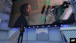 Google CEO Sundar Pichai speaks under a video showing singer John Legend at the Google I/O conference in Mountain View, Calif., Tuesday, May 8, 2018. (AP Photo/Jeff Chiu)
