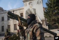 A Syrian opposition fighter holds a rocket launcher in front of the provincial government office, where an image of Syrian President Bashar Assad is riddled with bullets on the facade, in the aftermath of the opposition's takeover of Hama, Dec. 6, 2024.