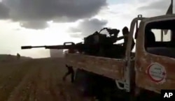 This frame grab from video provided by Baladi News Network, a Syrian opposition media outlet, is said to show Turkey-backed Syrian opposition fighters fire their weapons during clashes near the northern Syrian town of al-Bab, Aleppo province, Syria.