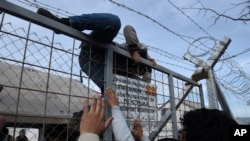 یک مهاجر افغان در حال عبور از موانع مرزی میان یونان و مقدونیه