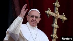 Pope Francis waves after delivering his "Urbi et Orbi" (to the city and the world) message from the balcony overlooking St. Peter's Square at the Vatican, Dec. 25, 2016. 