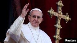 Pope Francis waves after delivering his "Urbi et Orbi" (to the city and the world) message from the balcony overlooking St. Peter's Square at the Vatican, Dec. 25, 2016. 
