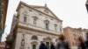 La gente camina junto a la iglesia de San Luis de Francia en Roma, el domingo 1 de marzo de 2020. La iglesia de la comunidad francesa en Roma, San Luis de los franceses, cerró sus puertas al público el domingo, según los informes, después de que un sacerdote fue infectado con el 