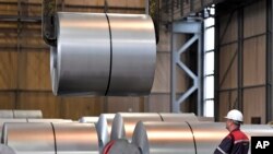 FILE - A worker moves steel coils at the Thyssenkrupp steel factory in Duisburg, Germany, April 27, 2018. 