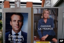 Election campaign posters for French centrist presidential candidate Emmanuel Macron and far-right candidate Marine Le Pen are posted in front of the polling station where Marine Le Pen will vote in Henin Beaumont, northern France, May 6, 2017.