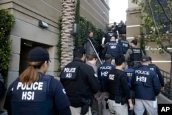 Federal agents enter an upscale apartment complex, Tuesday, March 3, 2015, in Irvine, Calif. Shortly after sunrise, federal agents swarmed the complex in the Orange County where authorities say a birth tourism business charged pregnant women $50,000...