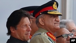 FILE - Pakistan's Army Chief Gen. Qamar Javed Bajwa, center, watches a parade with Prime Minister Imran Khan, left, and President Arif Alvi, in Islamabad, Pakistan, March 23, 2019.