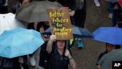 FILE - A man displays a placard as protesters gather in Hong Kong, Aug. 18, 2019. 