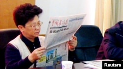 FILE - Yang Xiuzhu reads newspaper during meeting in Wenzhou, Zhejiang province, China, Dec. 29, 2001.