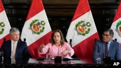 La presidenta de Perú, Dina Boluarte, muestra su collar, acompañada por sus abogados Mateo Castaneda, izquierda, y Eduardo Barriga, durante una conferencia de prensa en el Palacio de Gobierno en Lima, Perú, el viernes 5 de abril de 2024. 