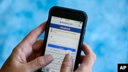 FILE - Facebook start page is shown on a smartphone in Surfside, Fla. 