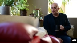 Omar Mediavilla, who urges his brother Jerick (Florida resident) to exercise the right to vote that the island's residents do not have, drinks a cup of coffee at his balcony in Toa Alta, Puerto Rico, Oct. 18, 2020. 