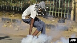 Seorang warga Sudan mengambil kaleng gas air mata dalam bentrokan yang terjadi antara para pengunjuk rasa dan polisi dalam aksi protes menentang kudeta militer, di Khartoum, Sudan, pada 4 Januari 2022. (Foto: AFP)