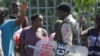 A resident stares at a Haitian National Police officer during a protest outside of Monte Cristo Hotel, designated as a coronavirus quarantine facility, in Port-au-Prince, Haiti March 12, 2020. Haiti has yet to confirm any cases of the new virus. 