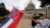 Larry Eubanks waves the current Mississippi state flag as he sits before the front of the Capitol, June 27, 2020, in Jackson, Miss. 