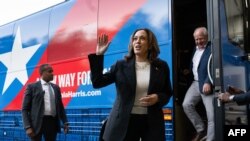 TOPSHOT - Democratic presidential candidate US Vice President Kamala Harris and her running mate, Minnesota Governor Tim Walz, disembark from their campaign bus in Savannah, Georgia, August 28, 2024, as they travel across Georgia for a 2-day campaign bus 