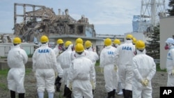 International Atomic Energy Agency (IAEA) inspection team members watch No.3 reactor at the crippled Tokyo Electric Power Co. Fukushima Daiichi nuclear power plant in Fukushima Prefecture, in this handout photo taken and released by TEPCO on May 27, 2011.