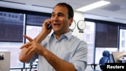 Reuters journalist Jason Szep is congratulated by a colleague on the phone in the Reuters Washington bureau after it was announced Szep and Reuters had won a Pulitzer prize for international reporting on the violent persecution of a Muslim minority in Burma, April 14, 2014.