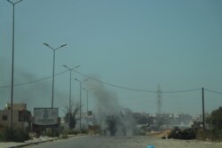 FILE - A tank burns in the distance after being hit by an airstrike, July 7, 2019 in Tripoli, Libya. (Heather Murdock/VOA)