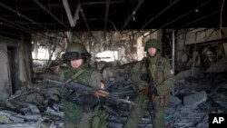 Russia-backed rebels walk in the destroyed building of the airport outside Donetsk, Ukraine, Wednesday, Feb. 25, 2015.