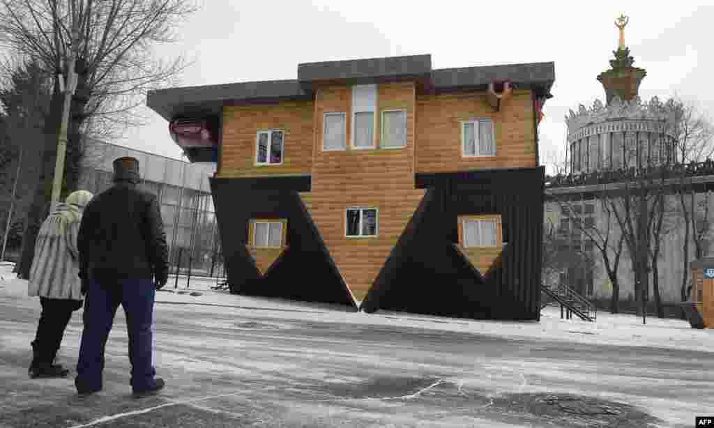 Pengunjung melihat sebuah &quot;rumah terbalik&quot; dalam pameran di Moskow, Rusia.