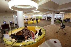 FILE - Northeastern University graduate student Shabbir Hussain, of Indore, India, left, views a computer screen at the entrance to the Snell Library on the Northeastern University campus in Boston, May 24, 2016.