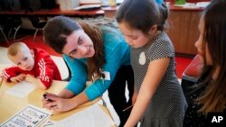 FILE - Language arts teacher Jennifer Walters helps students with their homework during an after-school program at Circleville Elementary School, in Circleville, Ohio, March 29, 2017.