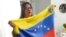 ARCHIVO - La venezolana Yuly Macedo porta una bandera de su país durante una entrevista en Davie, Florida, el jueves 11 de julio de 2024. 