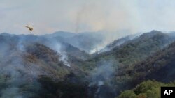 FILE - This photo provided by the Hawaii Department of Land and Natural Resources shows an Army helicopter carrying water to douse a wildfire burning east of Mililani, Hawaii, on Nov. 2, 2023.