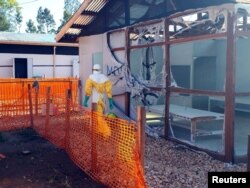 A health worker dressed in a protective suit walks past burned structures after attackers set fire to an Ebola treatment center run by Medecins Sans Frontieres (MSF) in the east Congolese town of Katwa, Democratic Republic of Congo, Feb. 25, 2019. MSF has since suspended work there.