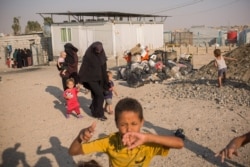 Women in the Ain Issa Camp carry their children, while boys play, in an area set aside for foreigners who came from all over the world to join IS, Sept. 1, 2019. (Yan Boechat/VOA)