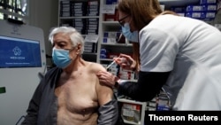 A pharmacist administers the AstraZeneca COVID-19 vaccine to a patient in a pharmacy in Paris as part of the coronavirus disease vaccination campaign, March 19, 2021.