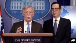 National security adviser John Bolton speaks as Treasury Secretary Steven Mnuchin listens during a press briefing at the White House, Jan. 28, 2019, in Washington. 