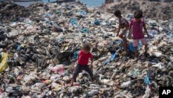 FILE - Palestinian children sort through trash in Nuseirat refugee camp, Gaza Strip, June 20, 2024. Israel's war in Gaza has decimated the strip's sanitation system, leaving many Palestinians living in tent camps near water contaminated with sewage and growing piles of garbage.
