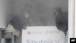 Trabajadores colocan una caja que contiene dosis de la vacuna rusa COVID-19 Sputnik V en un contenedor refrigerado después de descargarlo de un avión, en el Aeropuerto Internacional Simón Bolívar en Maiquetía, Venezuela. Febrero 13, 2021. Foto: AP.
