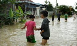 Girls wander through a flooded road in Spean Tmor commune, Dangkoa district, Phnom Penh City, Cambodia, on Oct. 14, 2020. (Malis Tum/VOA Khmer)