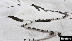 Hindu pilgrims cross a snow-covered mountain to reach the Amarnath cave shrine where they worship an ice stalagmite that Hindus believe to be the symbol of Lord Shiva, at Waval in the Kashmir region, July 6, 2019.