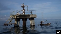 ARCHIVO - Un pescador navega cerca de una instalación petrolera en el Lago de Maracaibo, en el occidente de Venezuela, el 12 de octubre de 2022.
