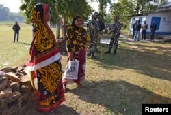 Women stand next to policemen as they wait to check their names on the draft list of the National Register of Citizens (NRC) at an NRC center in Chandamari village in Goalpara district, in the northeastern state of Assam, India, Jan. 2, 2018.