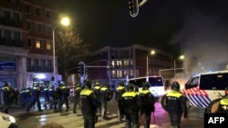 Riot police officers stand in position in a street of The Hague during a demonstration against the Dutch government's coronavirus measures, on November 20, 2021.