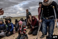 Men and boys suspected of being Islamic State (IS) fighters wait to be searched by members of the Kurdish-led Syrian Democratic Forces (SDF) after leaving the IS group's last holdout of Baghouz, in Syria's northern Deir Ezzor province, Feb. 27, 2019.
