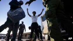 Agentes de la Patrulla Fronteriza registran y escoltan a hombres migrantes a una camioneta el viernes 15 de diciembre de 2023, cerca de Lukeville, Arizona.