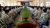 FILE - Policemen (center row) keep watch as inmates wait before being released from Hoang Tien prison, about 100 km (62 miles) outside Hanoi.