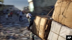 A man pulls a cart with merchandise past quake-damaged buildings in downtown Port-au-Prince, Haiti, 06 Jan 2011
