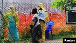 FILE - A woman and her child arrive for an Ebola-related investigation at the health facility at the Bwera hospital near the border with the Democratic Republic of Congo in Bwera, Uganda, June 14, 2019. 
