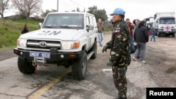 A Filipino United Nations peacekeeper stands next to a U.N. vehicle before it crosses from Israel into Syria at the Kuneitra border crossing on the Golan Heights, March 5, 2013. 